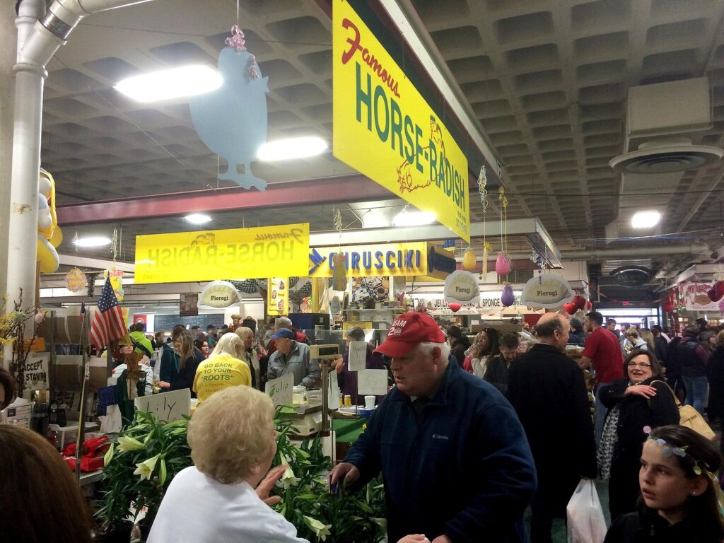 Shoppers crowding the Broadway Market in Buffalo before Easter, under signs for horseradish and chrusciki