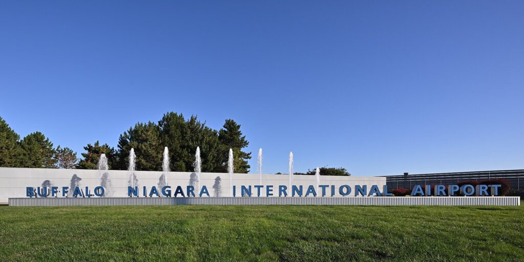 The Buffalo Niagara International Airport sign in front of a row of fountains under a blue sky