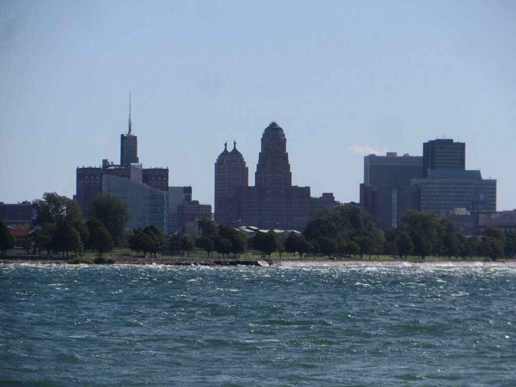 Downtown Buffalo's skyline with the Art Deco City Hall tower rising above the Niagara River, seen from Fort Erie, Ontario, for this Buffalo NY travel guide
