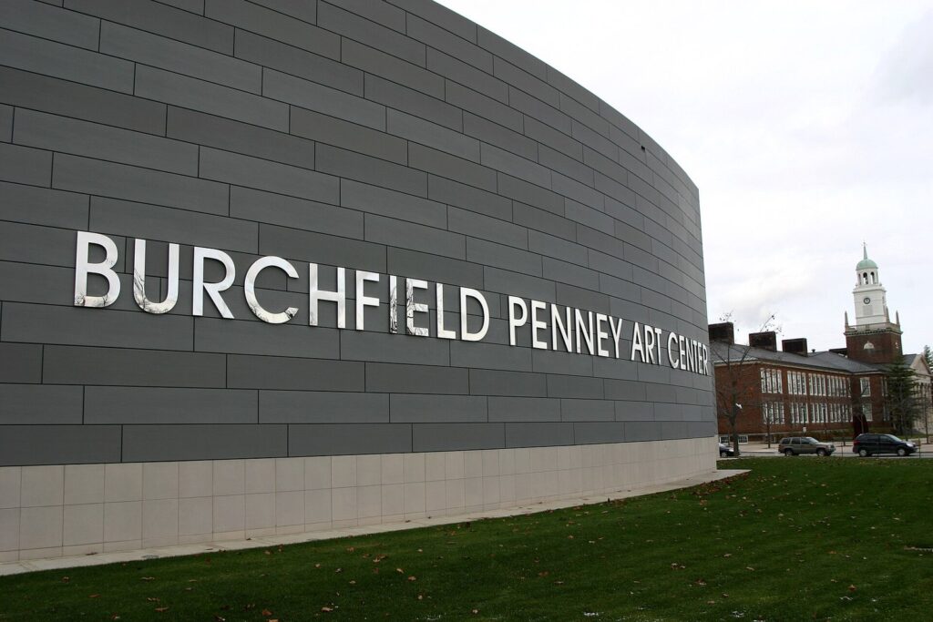 The curved gray facade of the Burchfield Penney Art Center with its name in large silver letters, on the SUNY Buffalo State campus