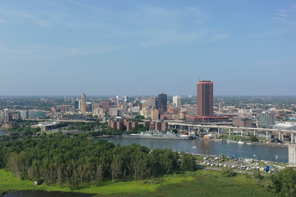 Aerial view across the Buffalo River to downtown Buffalo, NY, with City Hall's tower at left, the Naval Park's warships at the riverbank and the Skyway at right