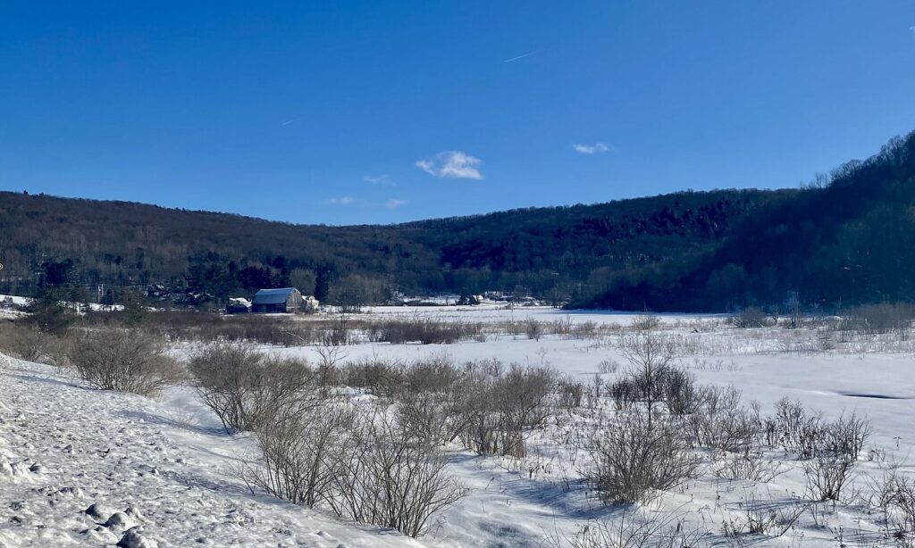 A snowy valley and wooded ridges near Ellicottville, New York, under a clear blue winter sky