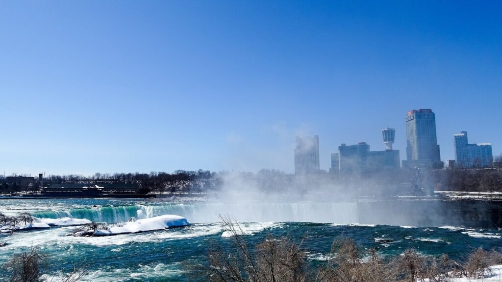 The Horseshoe Falls in winter seen from Goat Island, with snow on the banks and ice-coated trees