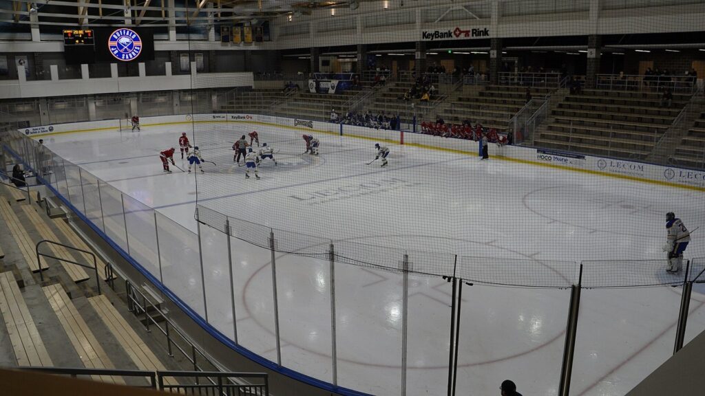 A hockey game on the ice at the KeyBank Rink inside LECOM Harborcenter, with spectators in the stands