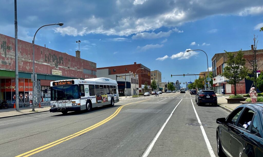 An NFTA Metro bus on Broadway in Buffalo passing the Broadway Market on a sunny day