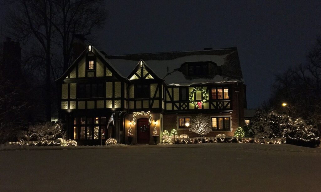 A Tudor-style house on Nottingham Terrace in Buffalo lit with Christmas lights and wreaths on a snowy night