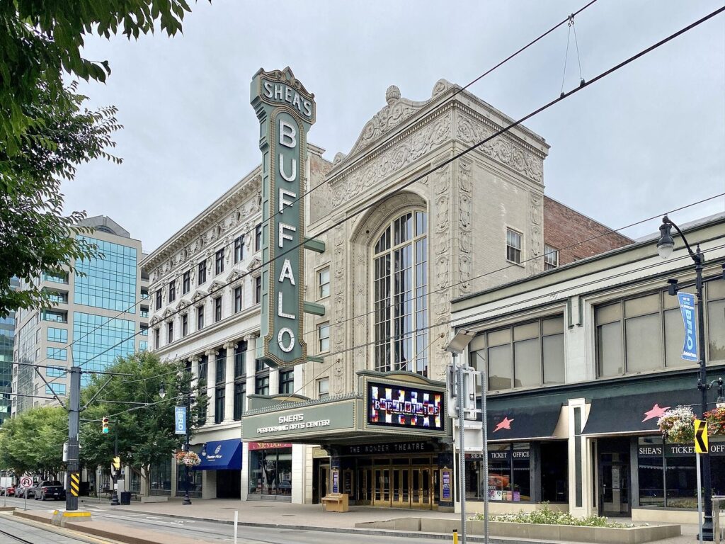 The vertical Shea's Buffalo sign and marquee on the ornate cream facade of Shea's Buffalo Theatre on Main Street