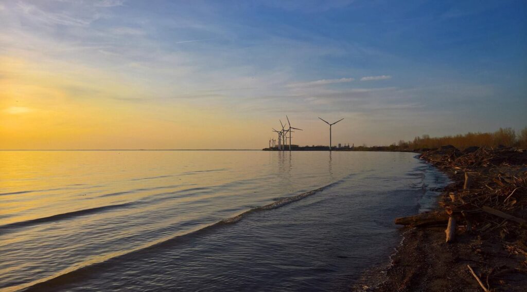 Sunset over Lake Erie from the shore at Woodlawn Beach State Park, with wind turbines on the horizon